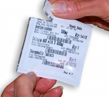 Hands opening a labeled medication pouch from an ATP strip