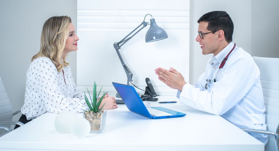 A healthcare professional and a woman discussing information across a desk